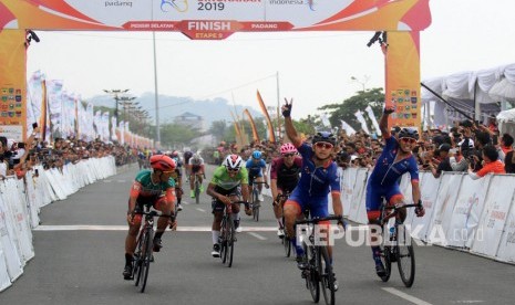 Pebalap Azman Muhammad Zawawi (tengah) mengangkat tangannya setelah memasuki garis finis saat mengikuti Tour De Singkarak 2019 etape kesembilan di Padang, Sumatera Barat, Ahad (10/11/2019).