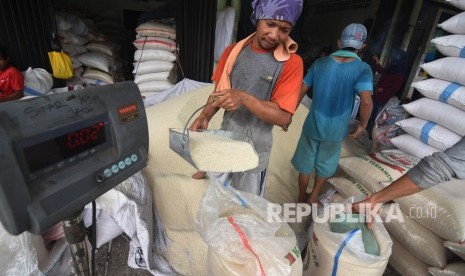 Pekerja mengemas beras ke dalam karung di Pasar Induk Beras Cipinang, Jakarta, Senin (11/11/2019).