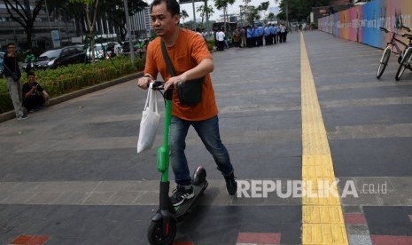 Pengendara skuter listrik melintas di trotoar Jalan Sudirman, Jakarta, Jumat (22/11/2019).