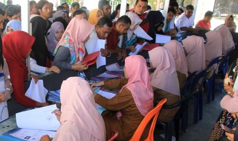 Puluhan pelamar Calon Pegawai Negeri Sipil (CPNS) antre untuk menyerahkan berkas pendaftaran lamaran di halaman komplek Dinas Pendidikan Kabupaten Aceh Barat, di Aceh, Senin (25/11/2019). 