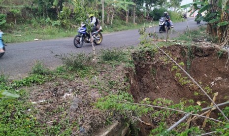 Warga melintas di Jalan Cisinga tepatnya di kilometer 4, Desa Karangsembung, Kecamatan Jamanis, Kabupaten Tasikmalaya, yang amblas akibat hujan besar, Selasa (26/11)