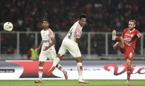 Gelandang Persija Jakarta Joan Tomas Campasol (kanan) dibayang-bayangi bek Persipura Jayapura Yohanis Tjoe (tengah) menendang bola yang menghasilkan gol pada laga lanjutan Liga 1 di Stadion Utama Gelora Bung Karno, Jakarta, Kamis (28/11/2019).