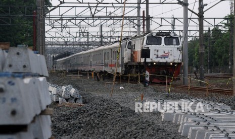 Rangkaian kereta api jarak jauh melintas di samping proyek pengerjaan jalur rel dwiganda atau double double track (DDT) lintas Cakung-Cikarang, di Bekasi, Jawa Barat, Senin (2/12/2019).