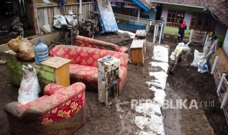 Warga membersihkan perabotan rumah tangga yang terkena lumpur pascabanjir bandang di Kertasari, Kabupaten Bandung.