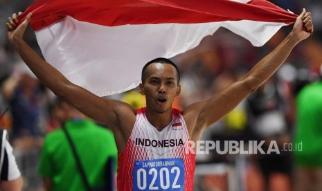 Atlet lompat jauh Indonesia Sapwaturrahman mengibarkan Bendera Merah Putih setelah berhasil memenangkan pertandingan Lompat Jauh Putra SEA Games ke-30 di Stadion Atletik New Clark, Filipina, Sabtu (7/12/2019)