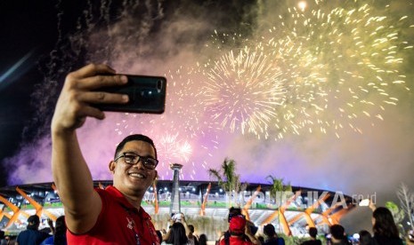 Seorang relawan melakukan swa foto dengan latar belakang kembang api saat penutupan SEA Games 2019 di Stadion Atletik New Clark City, Tarlac, Filipina, Rabu (11/12/2019). Tempat sampah berbentuk ring basket di Clark City menjadi daya tarik selama SEA Games 2019.