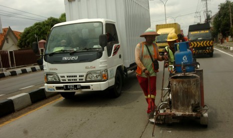 Pekerja melakukan pengecatan marka jalan di jalur Pantura Tegal, Jawa Tengah, Kamis (12/12/2019). 