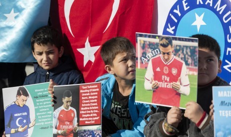 Para pemrotes Turki dan Uyghur memegang foto-foto pemain sepak bola Turki yang membela Arsenal Mesut Oezil karena pesan dukungannya kepada Turkestan Timur dan Uighur selama protes melawan Pemerintah China di Istanbul, Turki, 14 Desember 2019.