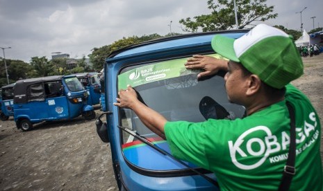 Pengemudi menempel stiker BPJS Ketenagakerjaan ke bajajnya di kawasan Pantai Carnaval Ancol, Jakarta Utara. BPJamsostek menyebut pengelolaan dana milik pekerja selalu diawasi OJK