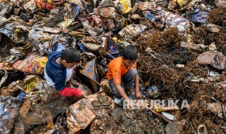 Anak-anak mencari sisa besi bekas di tumpukan limbah Bahan Beracun dan Berbahaya (B3) di Jakarta, Jumat (27/12/2019). 