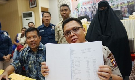 Kabid Humas Polda Gorontalo AKBP Wahyu Tri Cahyono (kanan) bersama penyidik menunjukKan barang bukti pada rilis pengungkapan kasus penipuan dan penggelapan penyelenggaraan perjalanan umrah di Mapolda Gorontalo, Kabupaten Gorontalo, Gorontalo, Jumat (27/12/2019).