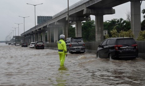 Petugas mengatur kendaraan yang melintasi genangan air ketika banjir merendam jalan Tol Cikampek di sekitar Jati Bening, Bekasi, Rabu (01/01/2020).