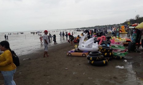 Meski cuaca mendung dan hujan gerimis, ribuan pengunjung tetap memadati objek wisata Pantai Karangsong, Kabupaten Indramayu, Rabu (1/1). Di hari libur tahun baru, jumlah pengunjung di pantai itu melonjak tinggi dibandingkan hari biasa. 