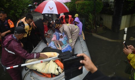 Petugas mengevakuasi warga yang sakit menggunakan perahu karet saat terjadi banjir di Perumahan Bukit Cengkeh 2, Depok, Jawa Barat, Rabu (1/1/2020). 