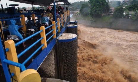 Sejumlah pengendara motor melintas diatas jembatan saat tinggi muka air sungai Ciliwung naik di Bendung Katulampa, Kota Bogor, Jawa Barat, Rabu (1/1/2020).