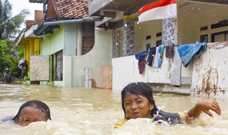 Dua orang anak bermain air saat banjir di Desa Karangligar, Karawang, Jawa Barat, Rabu (1/1/2020). Banjir Karawang mencakup 15 desa di enam kecamatan.