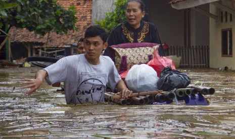 Warga mengevakuasi keluarganya mengunakan perahu rakit saat banjir di Desa karangligar, Karawang, Jawa Barat, Rabu (1/1/2020).