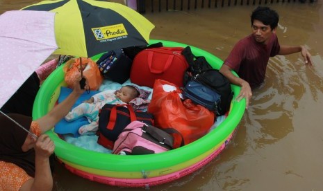 Warga dengan menggunakan perahu karet seadanya menyelamatkan bayinya dari dalam rumahnya yang terendam banjir di Perumaha Puri Bintaro Indah, Ciputat, Tangerang Selatan, Banten, Rabu (1/1/2020).