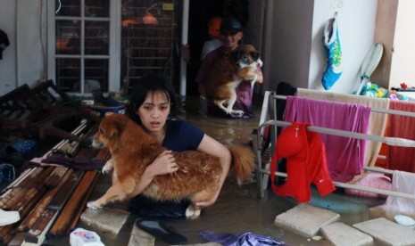 Warga menyelamatkan anjing peliharaannya dari dalam rumahnya yang terendam banjir di Perumaha Puri Bintaro Indah, Ciputat, Tangerang Selatan, Banten, Rabu (1/1/2020).