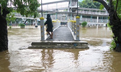 Seorang warga berada di atas jembatan Sungai Ciliwung yang meluap dan banjir menggenangi kawasan Pasar Baru di Jakarta Pusat, Kamis (2/1/2020). Kawasan perbelanjaan Pasar Baru, Jakarta Pusat pada Kamis (2/1), terpantau sepi.