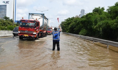 Petugas mengatur laju kendaraan yang melintasi banjir di jalan tol lingkar dalam Kebon Jeruk, Jakarta Barat, Kamis (2/1/2020). 