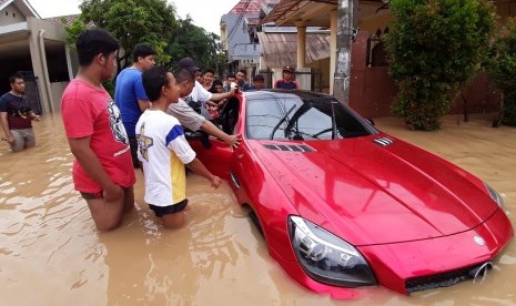 Sejumlah warga berusaha mendorong sedan mewah yang terjebak akibat banjir di Perumahan Vila Nusa Indah 1 RW 16, Kabupaten Bogor. Pemotret : Republika/Gunadi Supratman