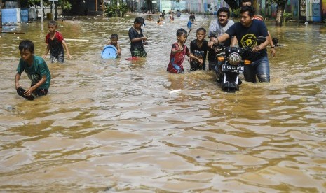 Warga melintasi banjir di kawasan Bukit Duri, Jakarta, Kamis (2/1/2020).