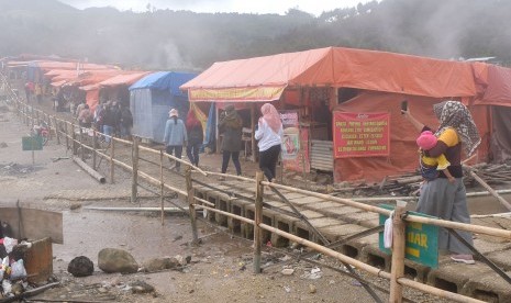 Wisatawan berjalan melintasi deretan tenda pedagang di kawasan wisata alam kawah Sikidang di dataran tinggi Dieng Desa Dieng Kulon, Batur, Banjarnegara, Jawa Tengah, Kamis (2/1/2020).