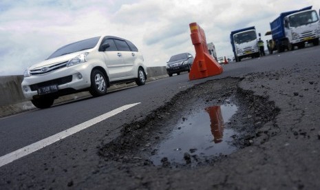 Sejumlah mobil melintas di jalan tol yang berlubang di tol. 