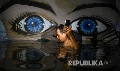 Seorang warga melintasi banjir di kawasan Kampung Baru, Kembangan, Jakarta Barat, Kamis (2/1/2020). 