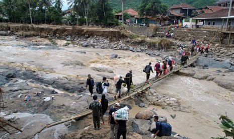 Sejumlah warga melewati jembatan darurat di atas sungai Cidurian, Desa Sukamaju, Kecamatan Cigudeg, Kabupaten Bogor, Jawa Barat, Jumat (3/1/2020).