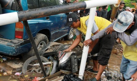 Petugas kebersihan dari Pemkot Tangerang mencoba menyingkirkan bangkai kendaraan yang terseret banjir di perumahan Ciledug Indah, Tangerang, Banten, Jumat (3/1/2020).