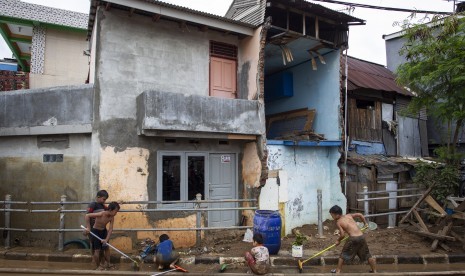 Sejumlah anak membersihkan endapan lumpur pascabanjir yang melanda kawasan Kampung Pulo, Jakarta, Jumat (3/1/2020).