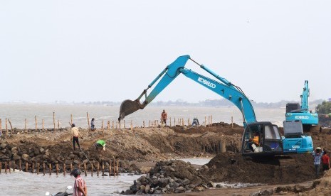 Pekerja menggunakan alat berat untuk memperbaiki tanggul pemecah ombak di pantai Dadap, Juntinyuat, Indramayu, Jawa Barat, Jumat (3/1/2020).