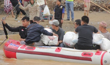 Warga membawa bantuan logistik dengan menggunakan perahu karet untuk korban banjir bandang di Lebak, Banten, Sabtu (4/1/2020). 