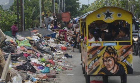 Pengguna jalan melaju di samping tumpukan sampah pascabanjir di Duren jaya, Bekasi, Jawa Barat, Ahad (5/1/2020).