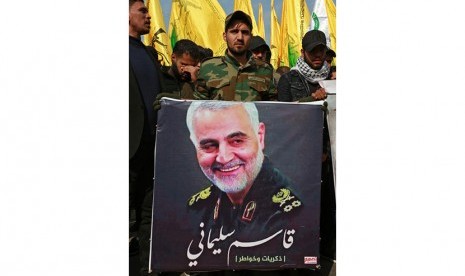 Seorang anggota kelompok bersenjata Syiah Irak yang didukung Iran pasukan mobilisasi populer membawa gambar Qassem Soleimani yang terbunuh di Baghdad tengah, Irak, 04 Januari 2020.