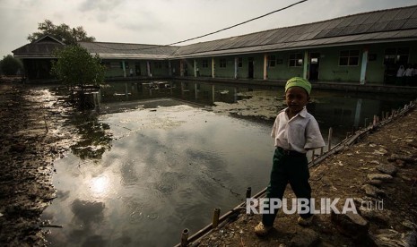 Siswa Madrasah Ibtidaiyah Mansyaul Huda berjalan di kawasan sekolah yang terkena abrasi di Kampung Beting, Pantai Bahagia, Muara Gembong, Kabupaten Bekasi, Jawa Barat.