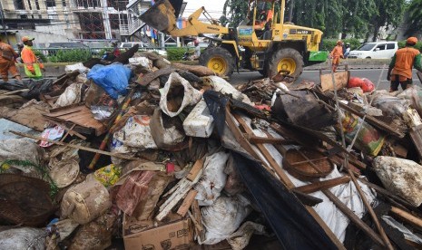 Petugas PPSU dibantu alat berat mengumpulkan sampah sisa banjir dari wilayah permukiman Bidara Cina, Jakarta. KLHK mengklaim telah menangani sampah dan kegiatan pertambangan di hulu sungai  