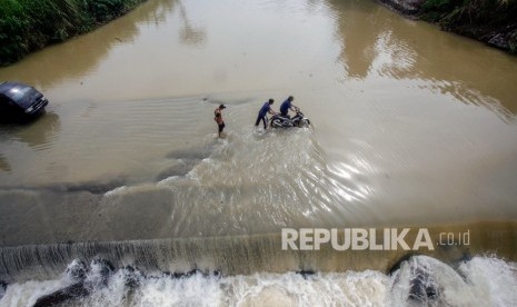 Pengendara roda dua memaksakan untuk melintasi jalan yang tergenang luapan air Sungai Cileungsi di Jalan alternatif Desa Gunung Sari, Citeureup, Kabupaten Bogor, Jawa Barat. (Ilustrasi)