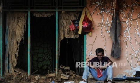 Seorang warga beristirahat di depan rumahnya yang rusak diterjang banjir bandang di Kampung Susukan, Lebak, Banten, Rabu (15/1/2020).