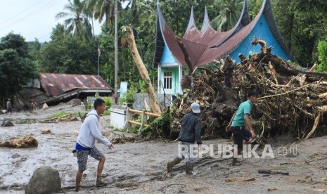 Warga melintas di depan rumah yang rusak diterjang banjir bandang, di Nagari Malalo, Tanah Datar, Sumatera Barat. Warga di Malalo masih khawatir akan terjadi banjir bandang. Ilustrasi.