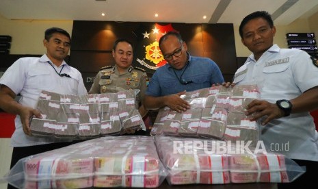 Polisi menunjukkan barang bukti uang rupiah saat ungkap kasus investasi ilegal 