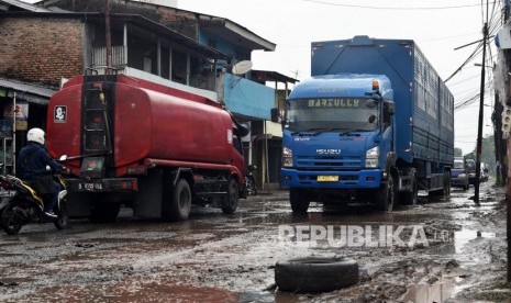 Pengendara memperlambat laju kendaraannya saat melintasi jalan rusak berlubang yang digenangi air dan lumpur di Jalan Pejuang, Pondok Ungu, Bekasi, Kamis (23/1/2020).