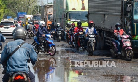 Sejumlah kendaraan melintasi jalan raya Kali Abang yang rusak di Bekasi, Jawa Barat, Kamis (23/1/2020).