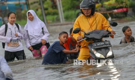 Warga melintasi banjir di Total Persada, Periuk, Kota Tangerang, Banten, Jumat (24/1/2020).