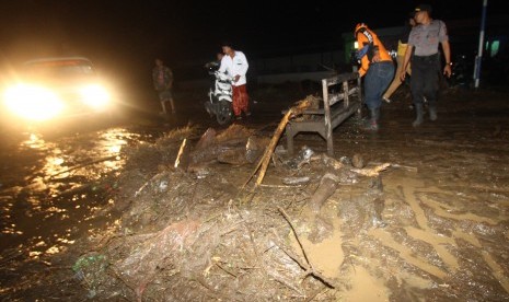 Warga membantu seorang pengendara motor melintas di jalan yang penuh lumpur saat terjadi banjir bandang di Petungsewu, Dau, Malang, Jawa Timur