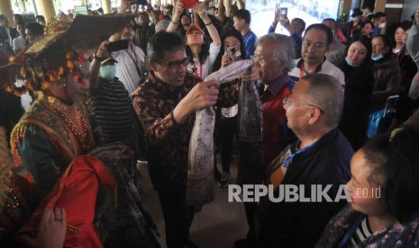 Gubernur Sumatera Barat Irwan Prayitno (kedua kiri) mengalungkan kain kepada salah satu wisatawan asal China saat penyambutan di Bandara Internasional Minangkabau (BIM), Padangpariaman, Sumatera Barat, Ahad (26/1/2020). 