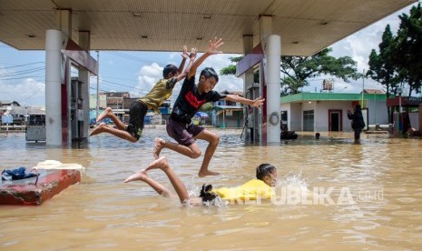 Sejumlah anak bermain di genangan banjir di Jalan Raya Baleendah, Kabupaten Bandung, Jawa Barat, Ahad (26/1/2020).