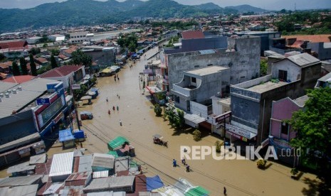 Warga melintas di genangan banjir di Jalan Raya Dayeuhkolot, Kabupaten Bandung, Jawa Barat, Ahad (26/1/2020).